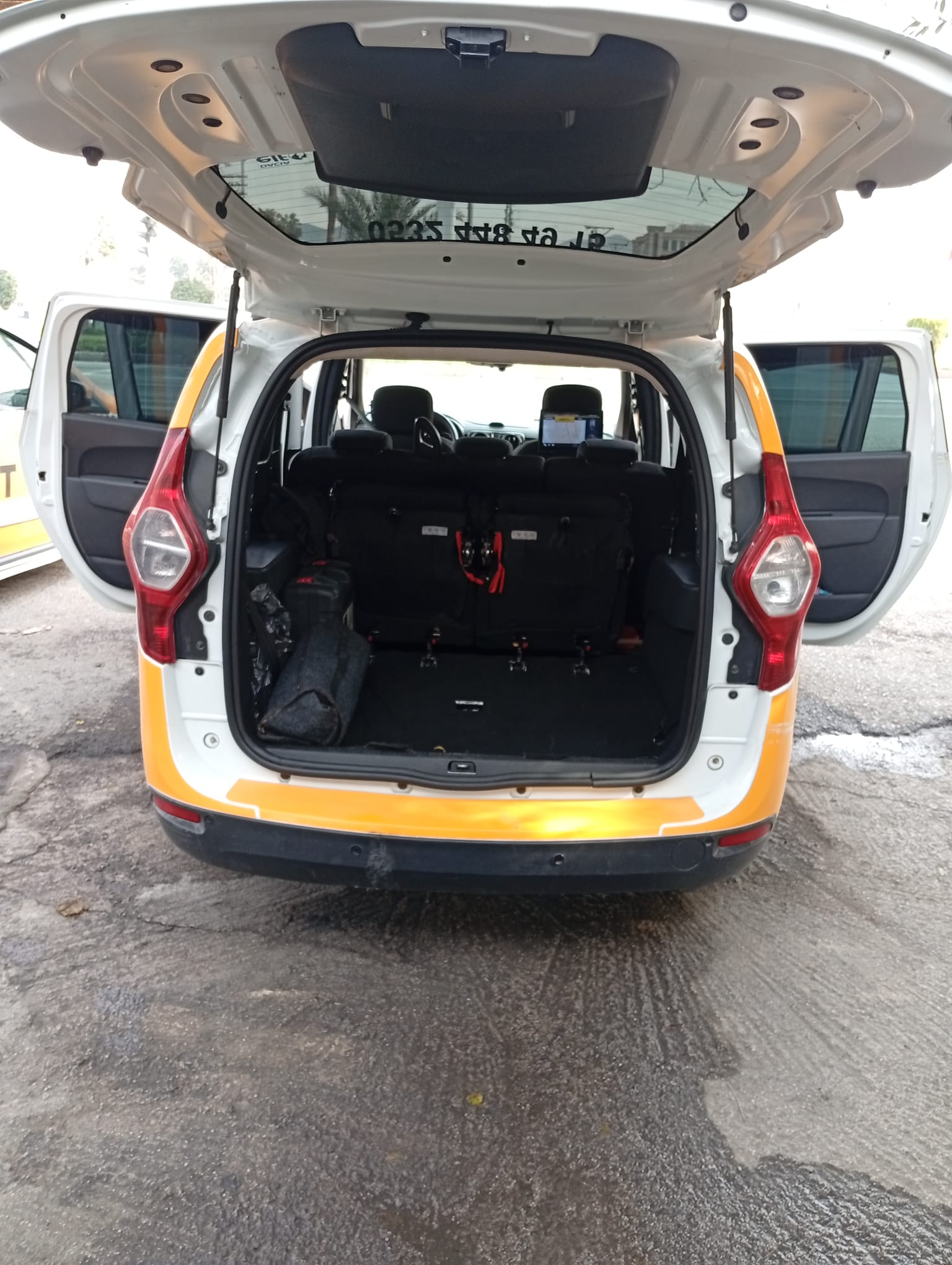 A wide-open trunk of a taxi, showcasing ample space for luggage and luggage straps in a clean vehicle.